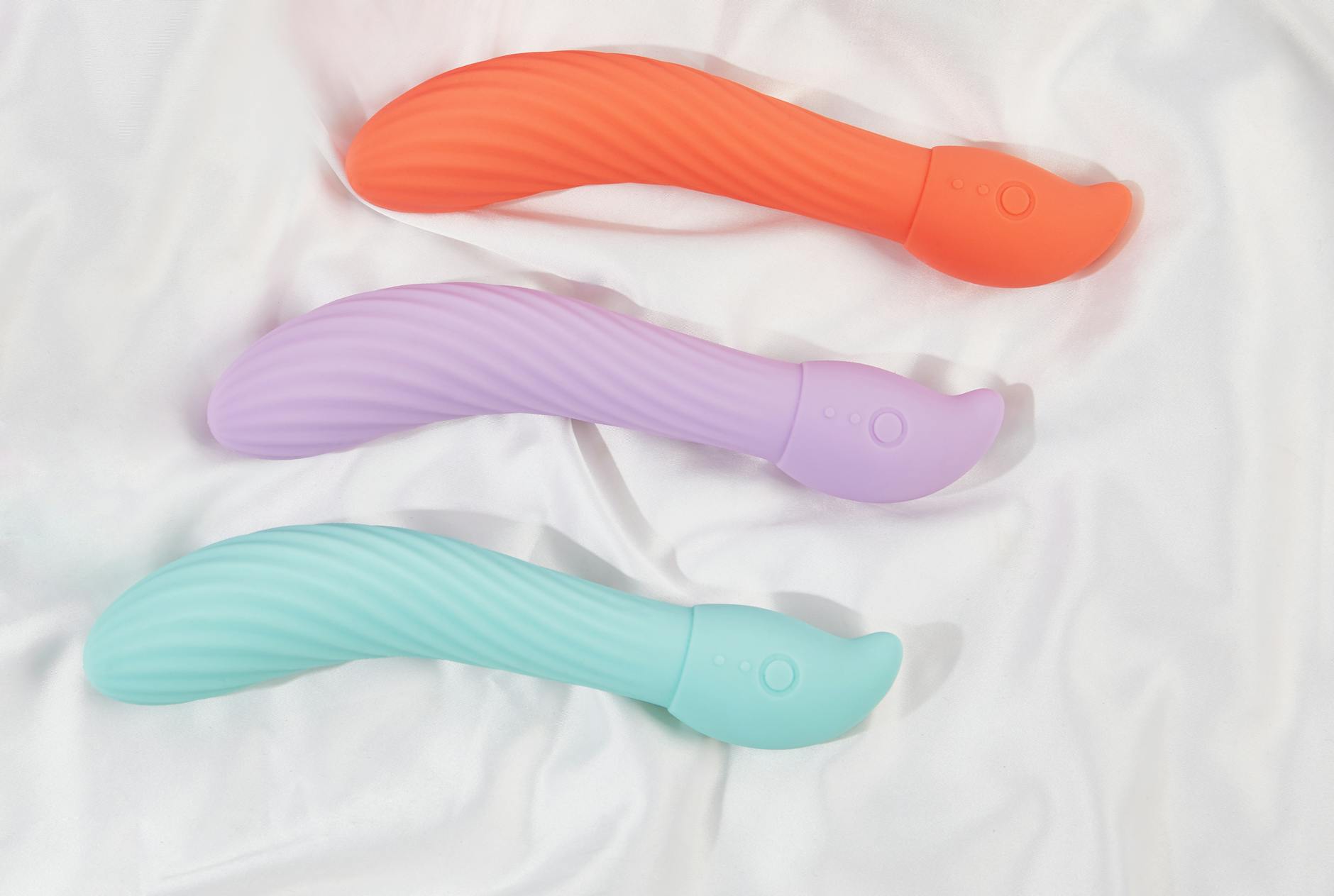 Ein stilvoller türkisfarbener Vibrator auf seidiger weißer Textur, symbolisiert Selbstliebe und Intimität