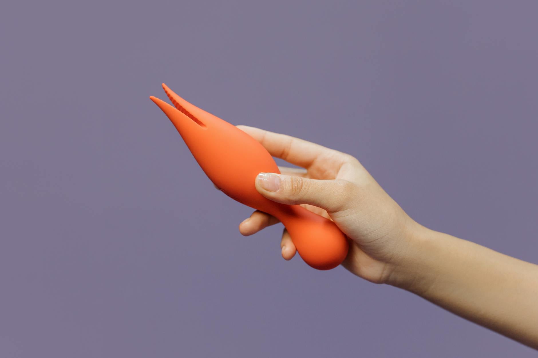 Eine Hand hält einen modernen Lemon-Vibrator gegen einen minimalistischen violetten Hintergrund, um zeitgenössische Sinnlichkeit zu zeigen.