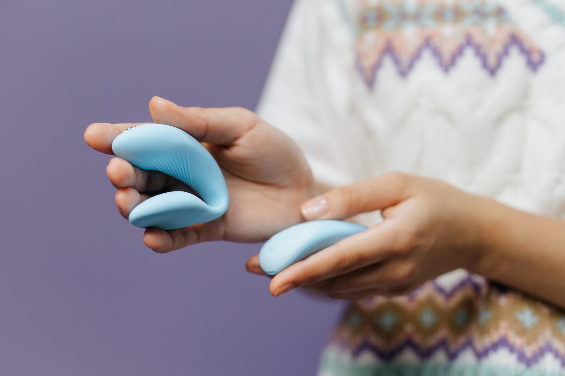 Hands holding a sleek blue lemon vibrator against a purple background, symbolizing intimacy and personal pleasure.